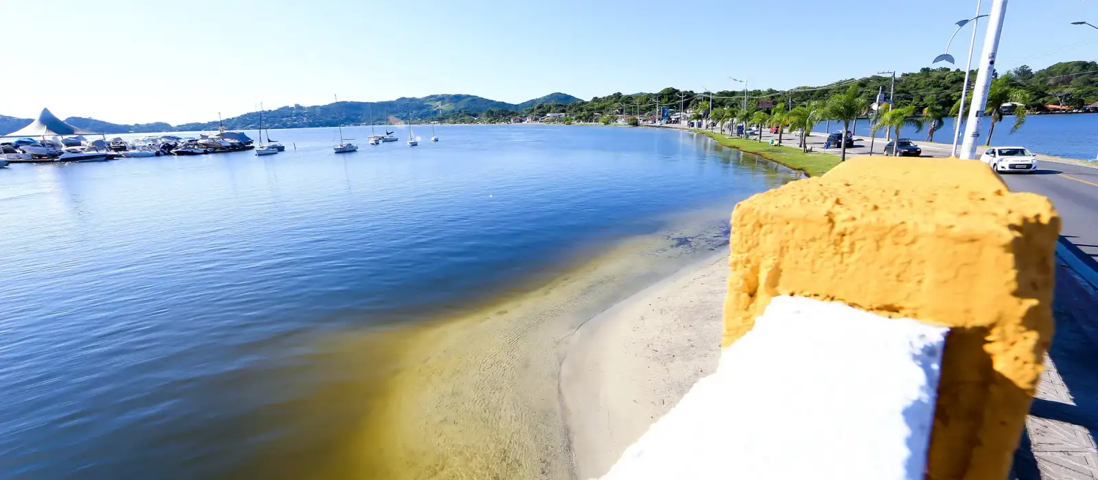 Costanera de la Lagoa da Conceição con el agua calma, los barcos y los cerros al fondo
