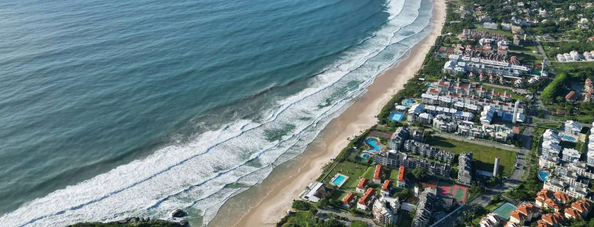 Vista aérea de uma praia do Norte da Ilha, com a faixa de areia e os prédios da orla