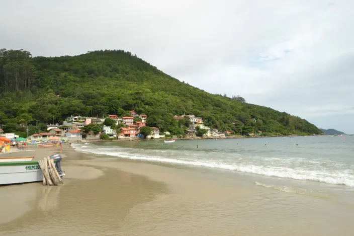 Arena del Pântano do Sul con barcos de pesca y las casas del pueblo en la ladera del cerro